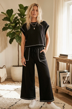 Load image into Gallery viewer, scuba lounge set in the color black featuring a relaxed cap sleeve top and matching wide leg pants. 
