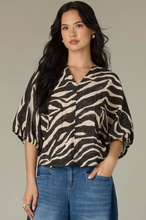 Load image into Gallery viewer, Woman wearing a zebra print top and blue jeans against a neutral background
